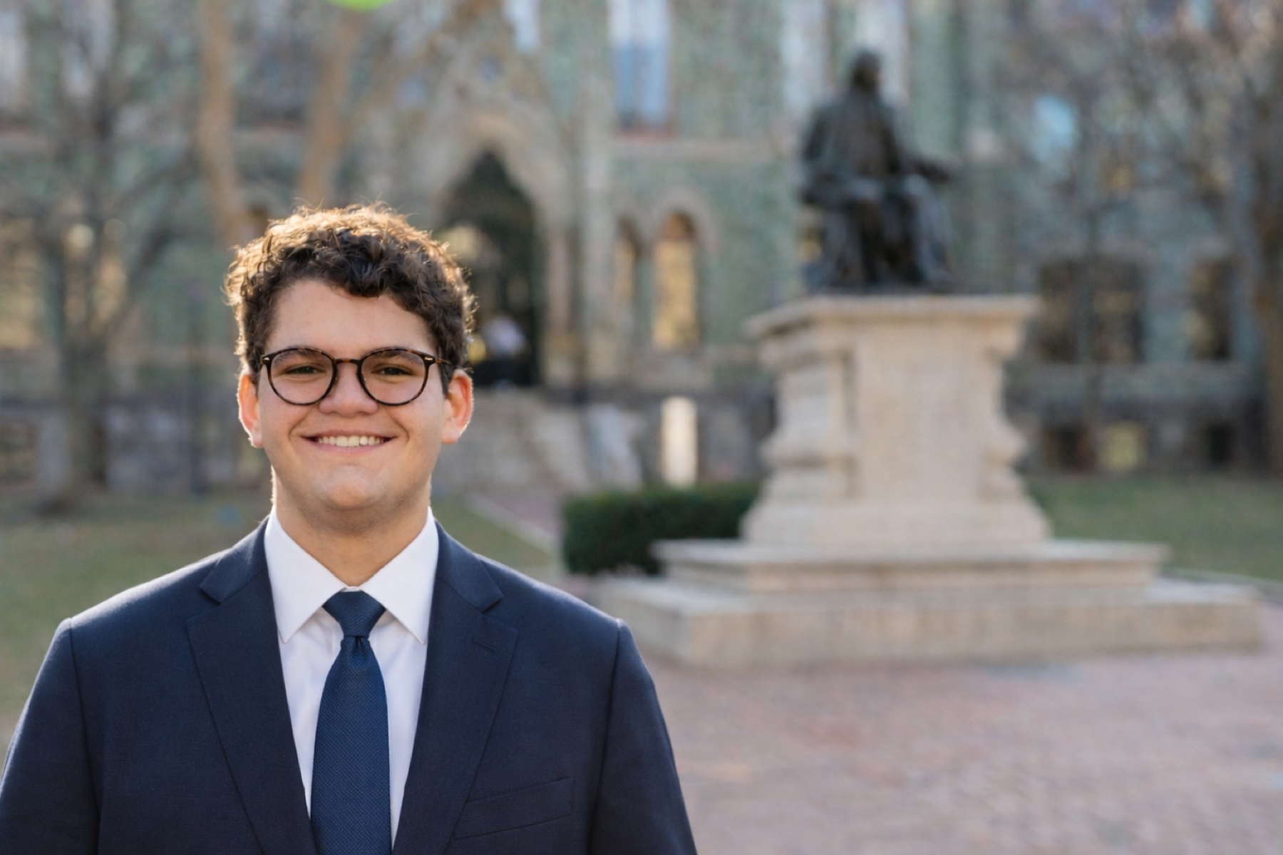 Noah Royal Milad in a navy suit on the University of Pennsylvania campus